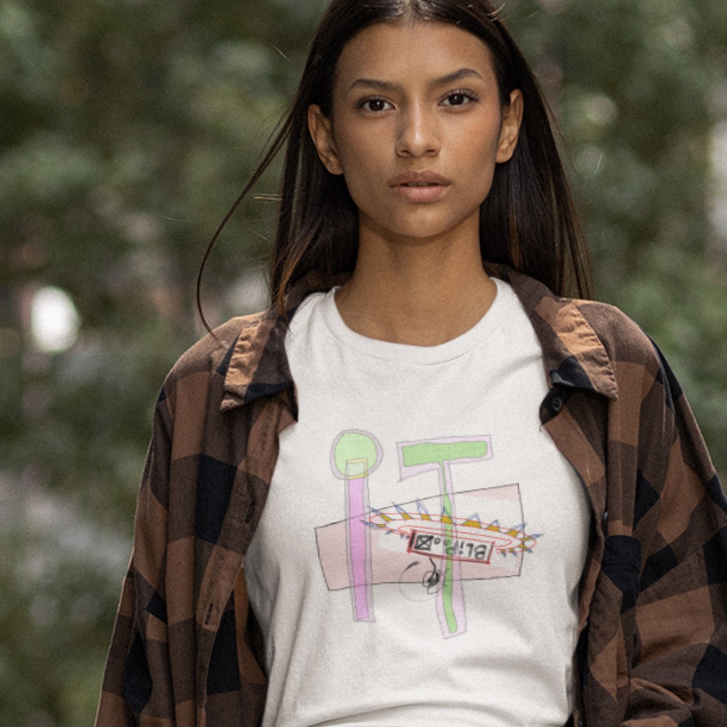 Woman wearing a white t-shirt with a colorful abstract drawing outside.