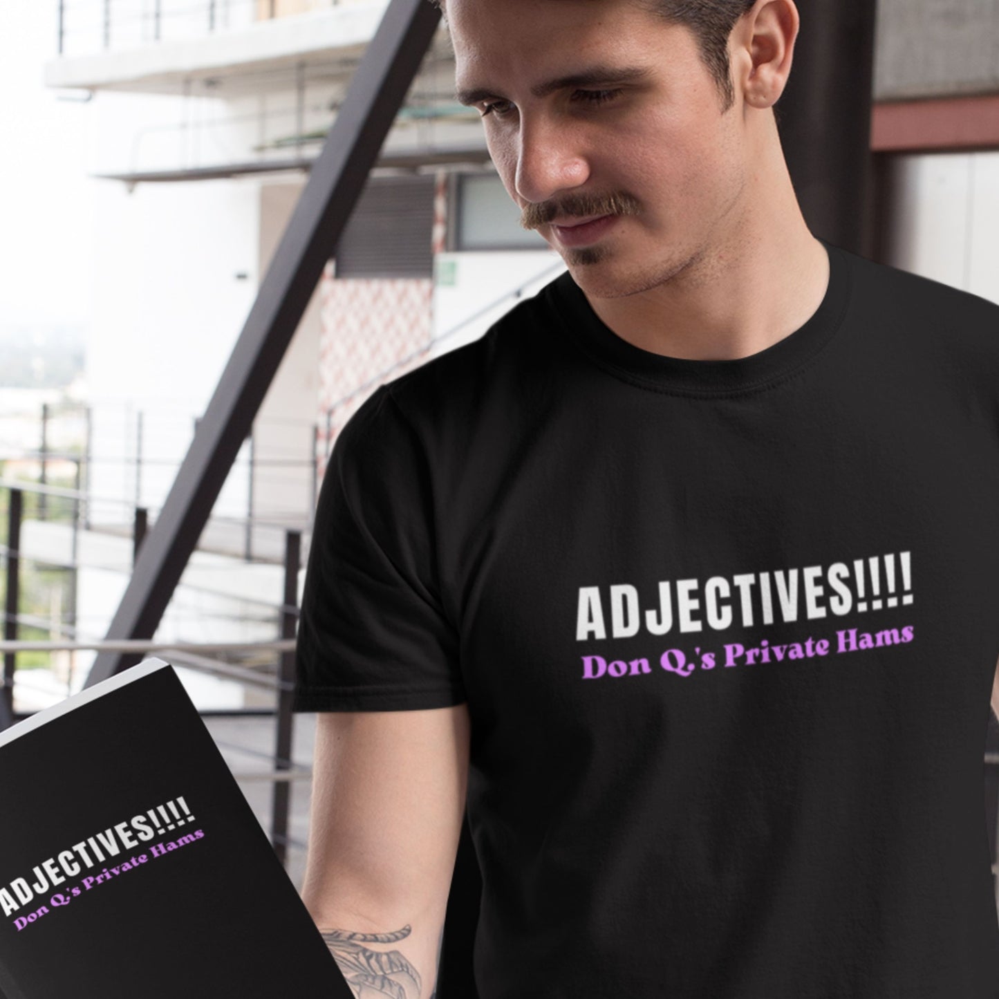 Man wearing a black t-shirt with humorous text design, holding a book with the same design.