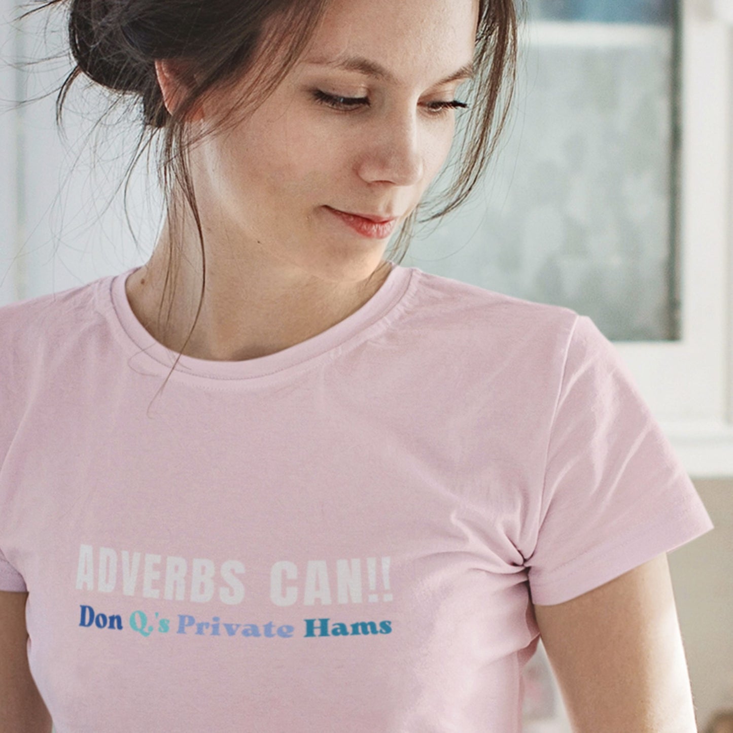 Woman wearing a pink t-shirt with text, sitting indoors.