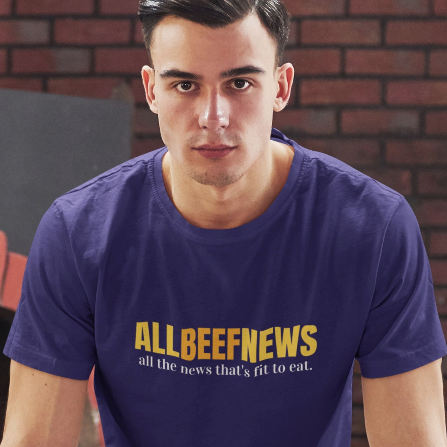 Serious man wearing a navy blue t-shirt with humorous colorful text in a school gym.