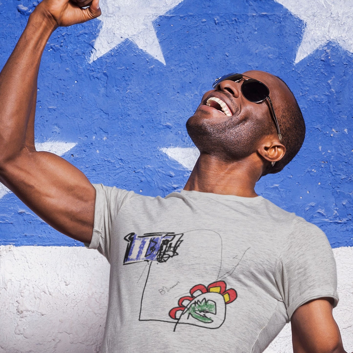 Happy man wearing an ash grey t-shirt with a colorful abstract drawing in front of a painted wall.
