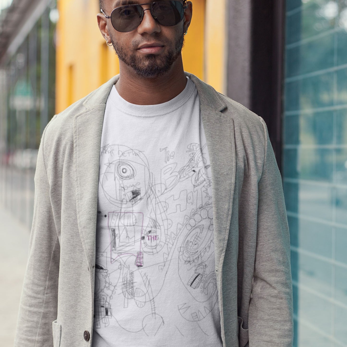 Man wearing a light gray cardigan over a graphic t-shirt with a city map design, standing outdoors.