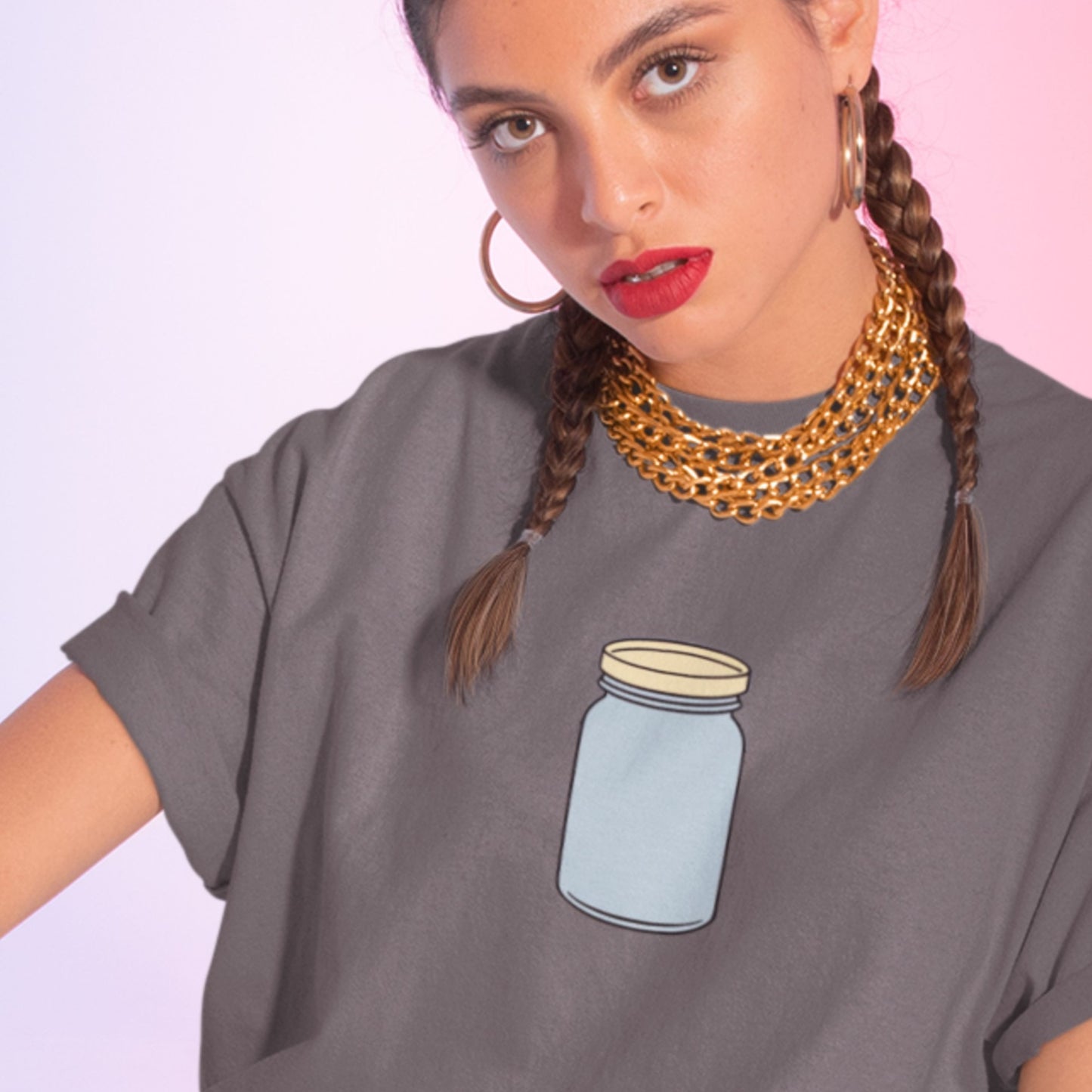 Woman wearing a grey t-shirt with a simple drawing of a blue jar with a beige lid on a multi-colored background.