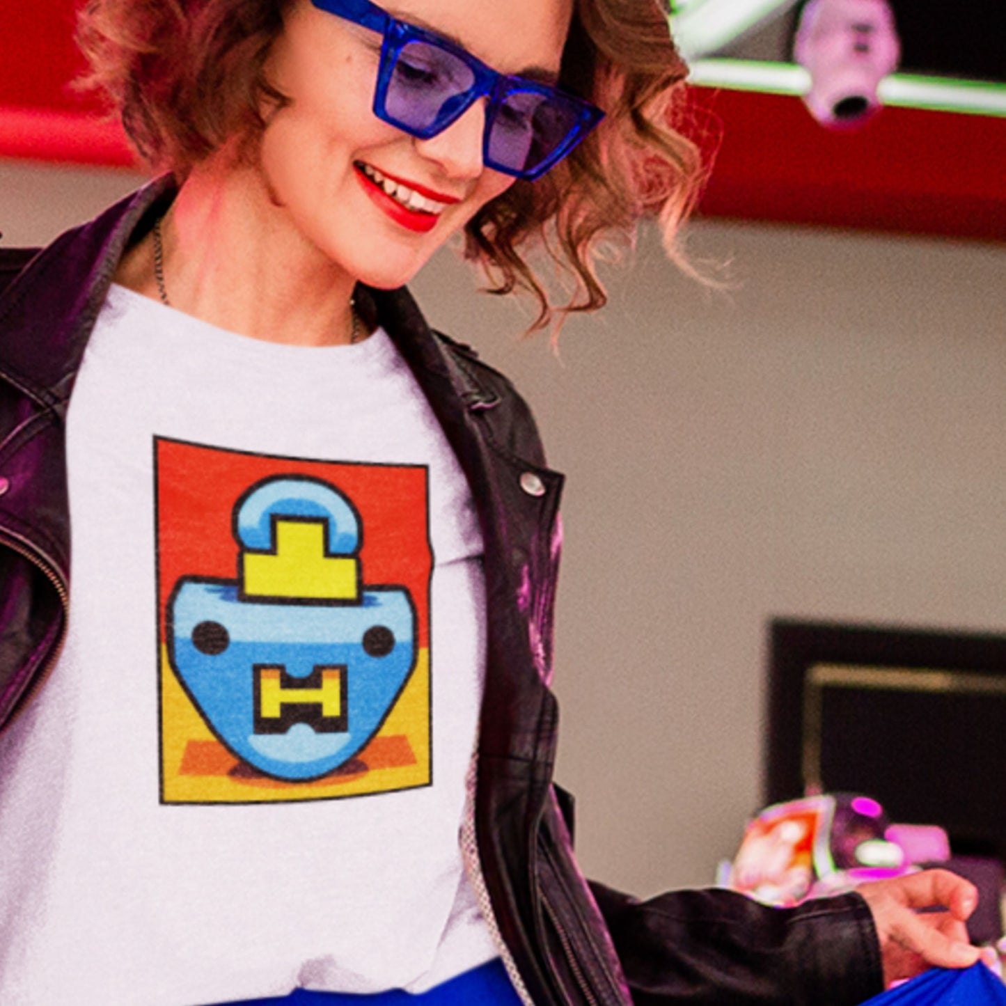 Person wearing a white t-shirt with a colorful graphic design, smiling indoors.