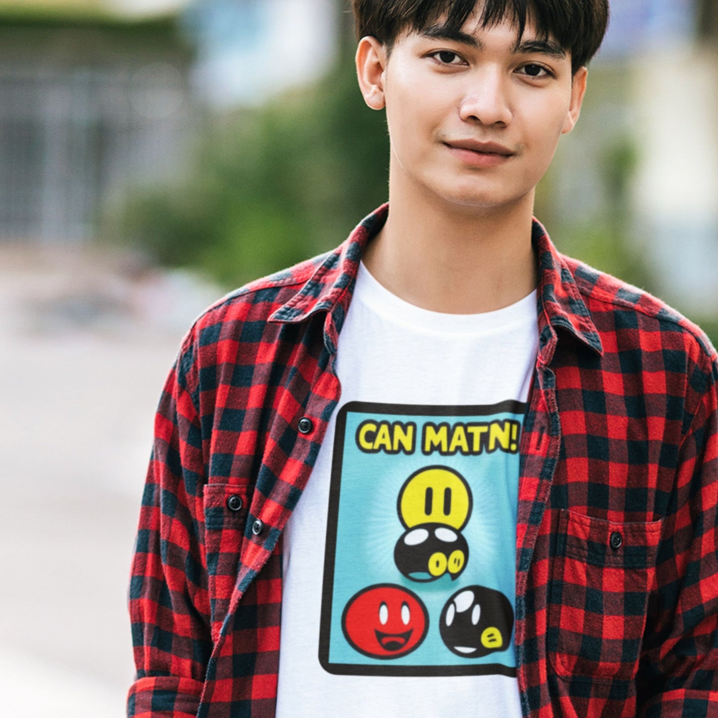 Man wearing a white t-shirt with a fun, colorful cartoon illustration outside.