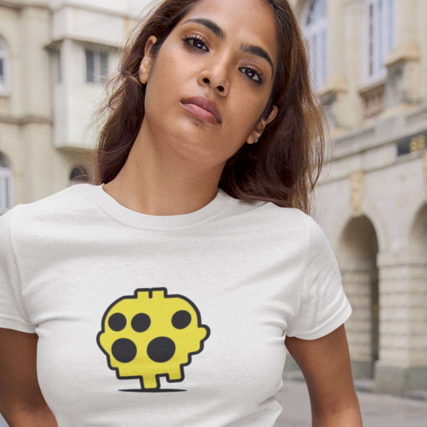 Woman wearing a white t-shirt with a yellow and black graphic design outdoors.