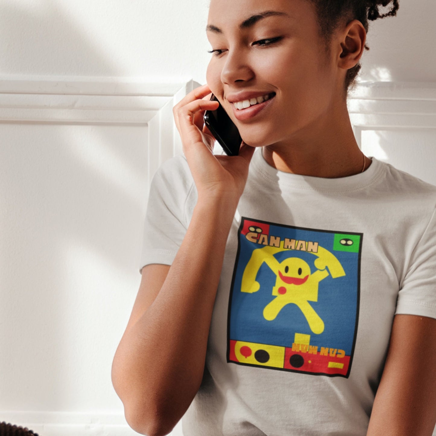 Woman wearing a white t-shirt with a colorful graphic design, talking on a phone.