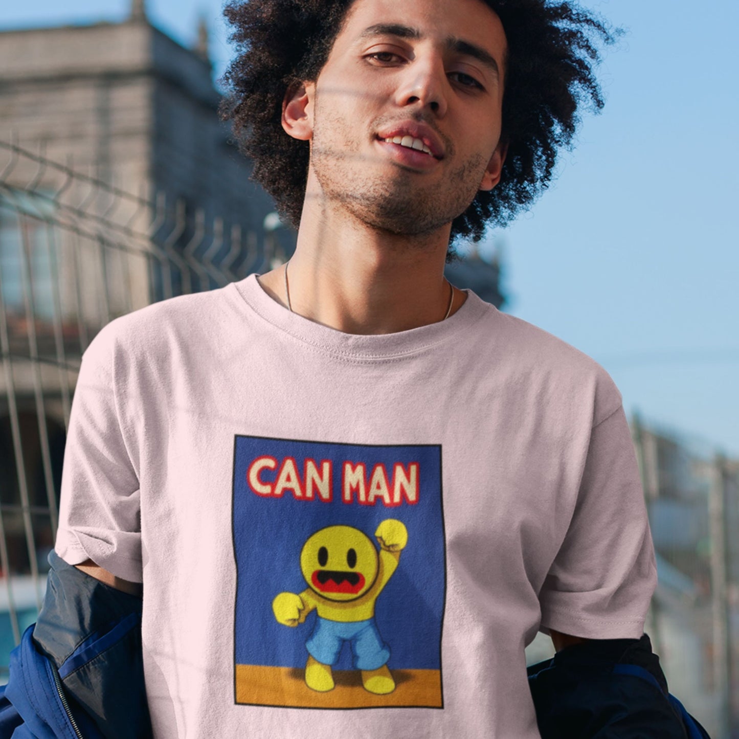 Man wearing a pink t-shirt with a fun, colorful cartoon illustration in a city.