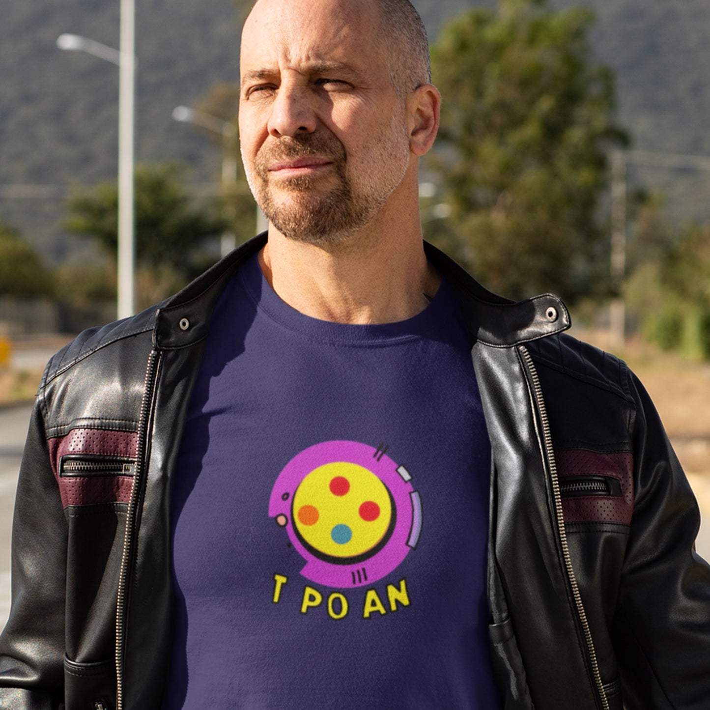 Gruff man wearing a navy blue t-shirt with a fun, colorful illustration on the side of the road.