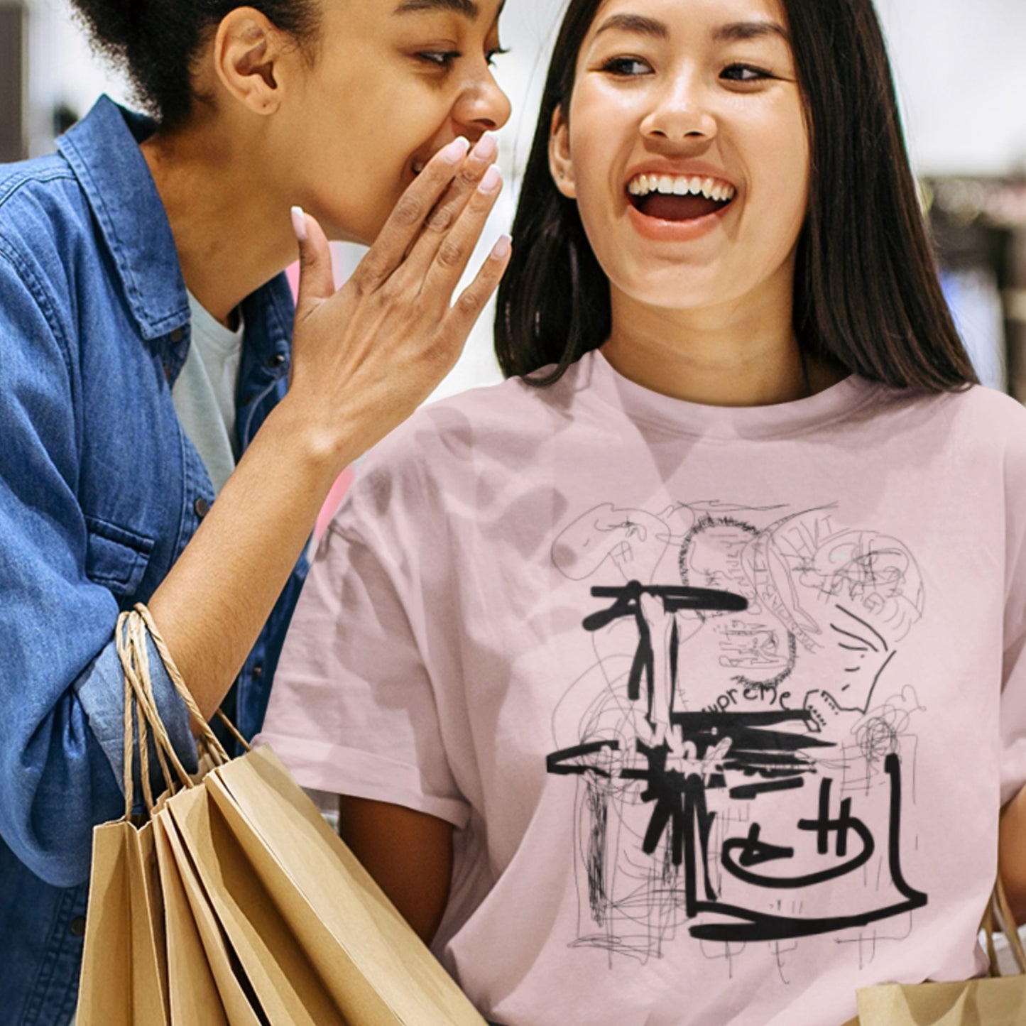 Two women laughing, one wearing a pink t-shirt with black graphics.