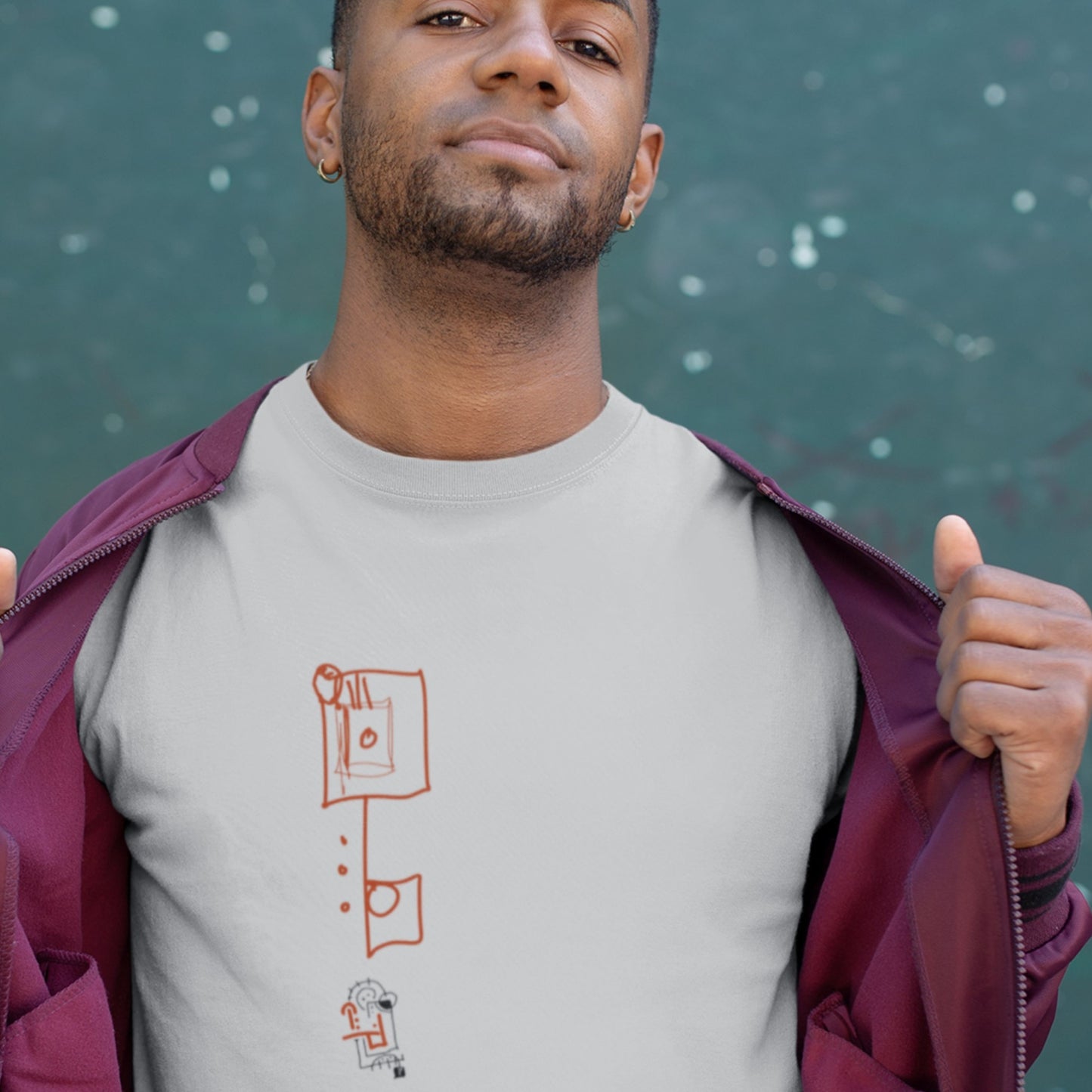 Man wearing a gray t-shirt with a graphic design and a purple jacket, standing against a dark background.