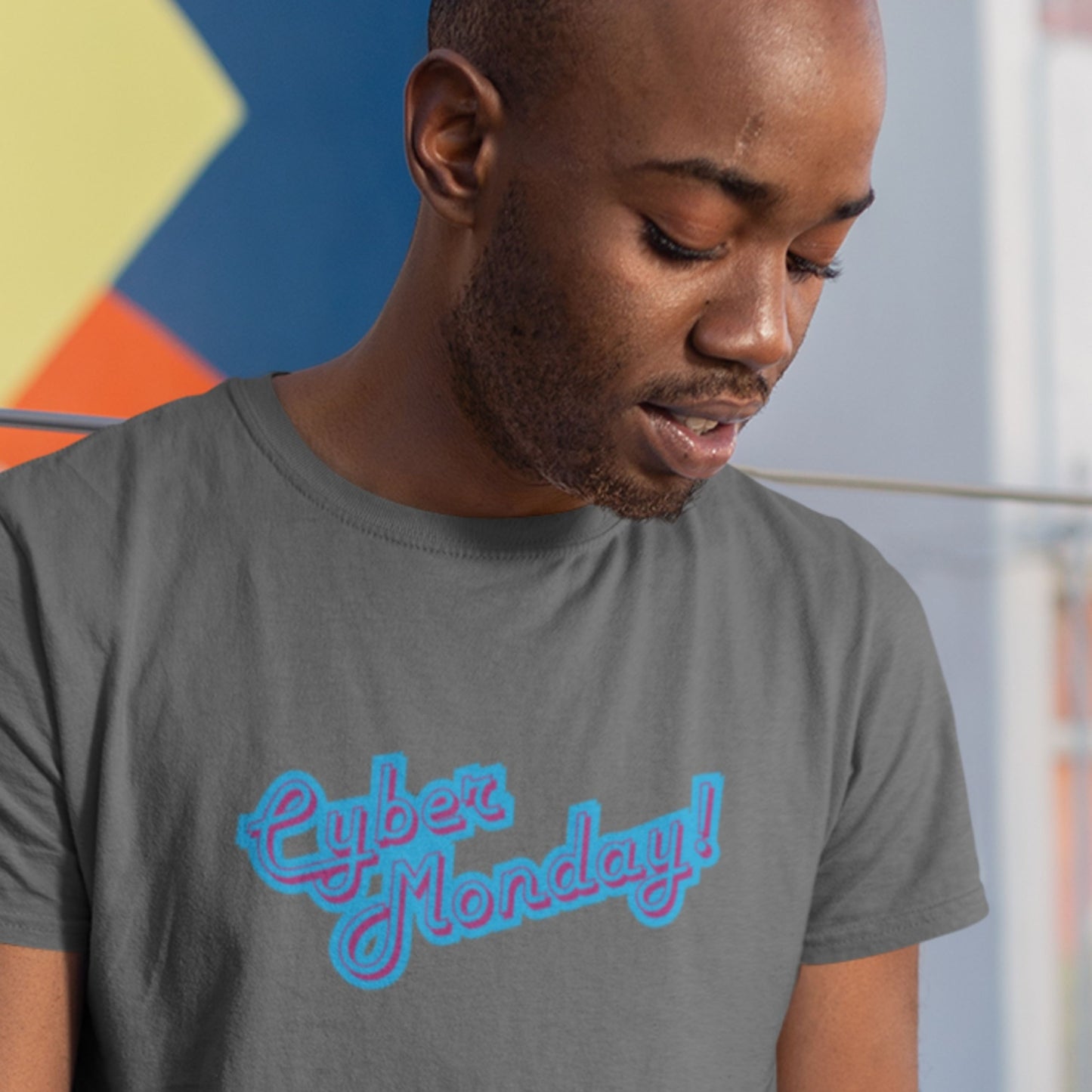 Man wearing a grey t-shirt with multicolored 'Cyber Monday!' text on a colorful background.