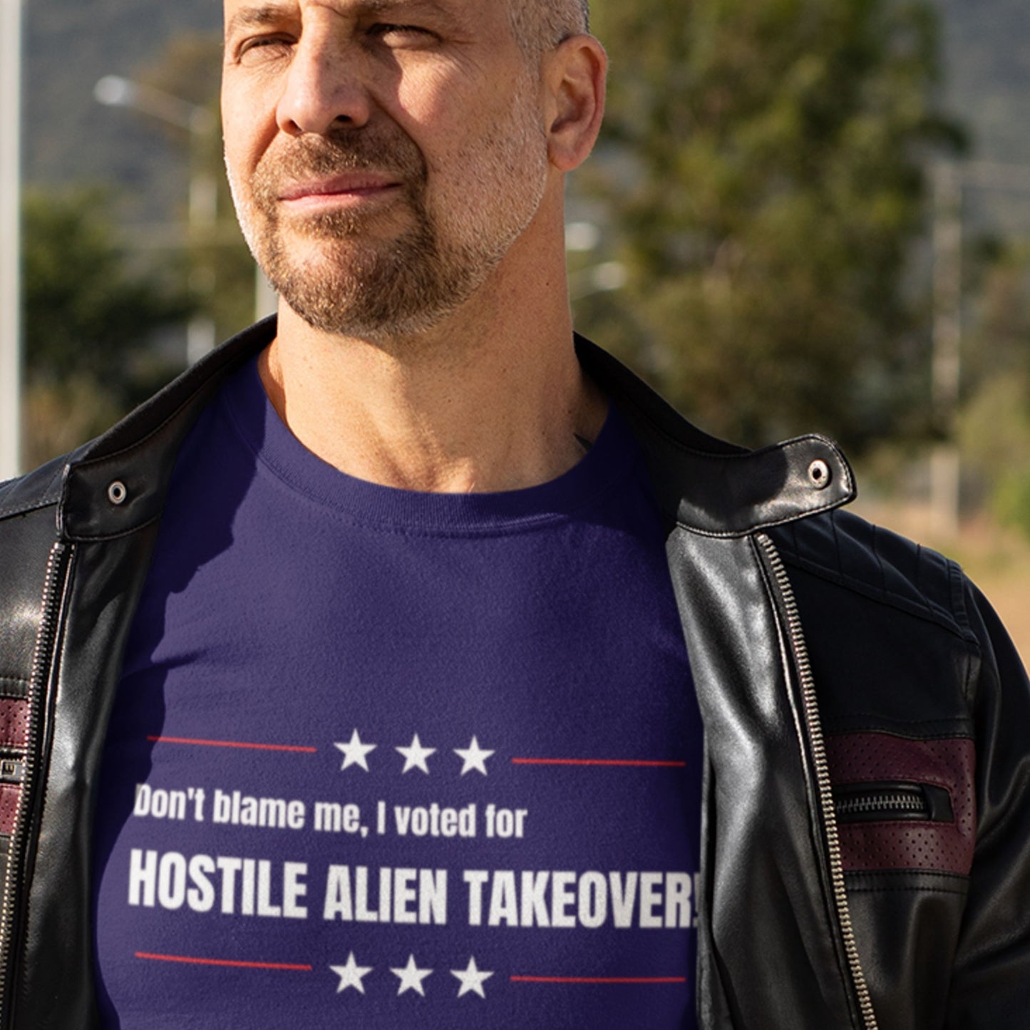 Man wearing a blue t-shirt with text outdoors.