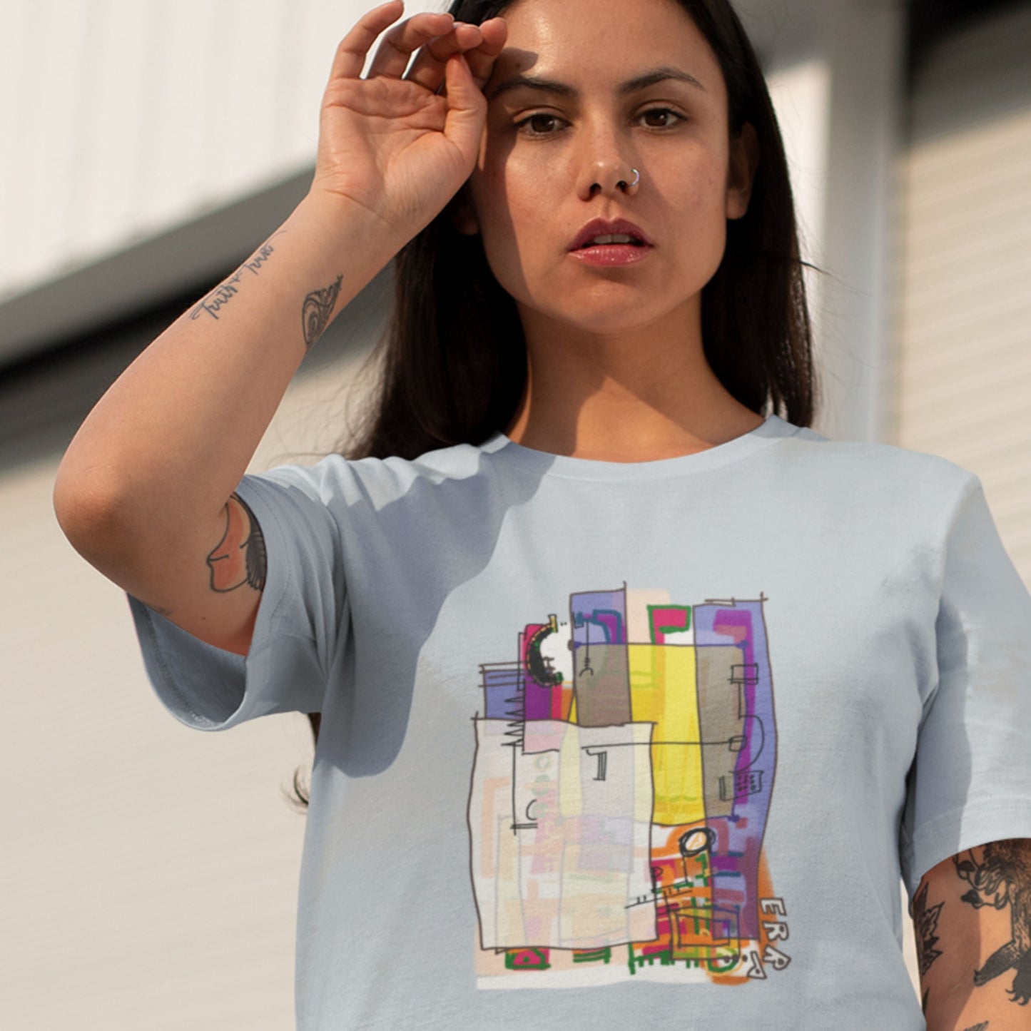 Woman wearing a light blue t-shirt with a colorful abstract diagram drawing outside.
