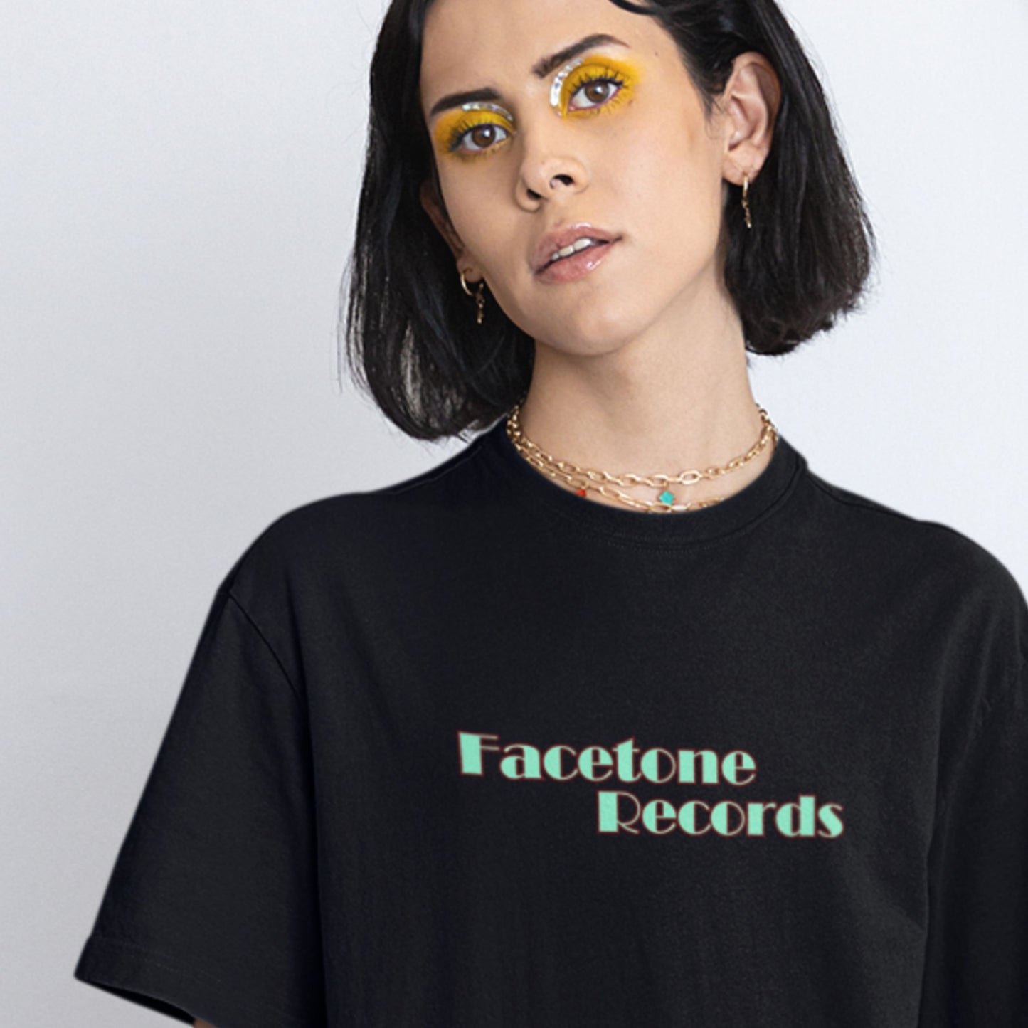 Person wearing a black t-shirt with 'Facetone Records' text on a plain background