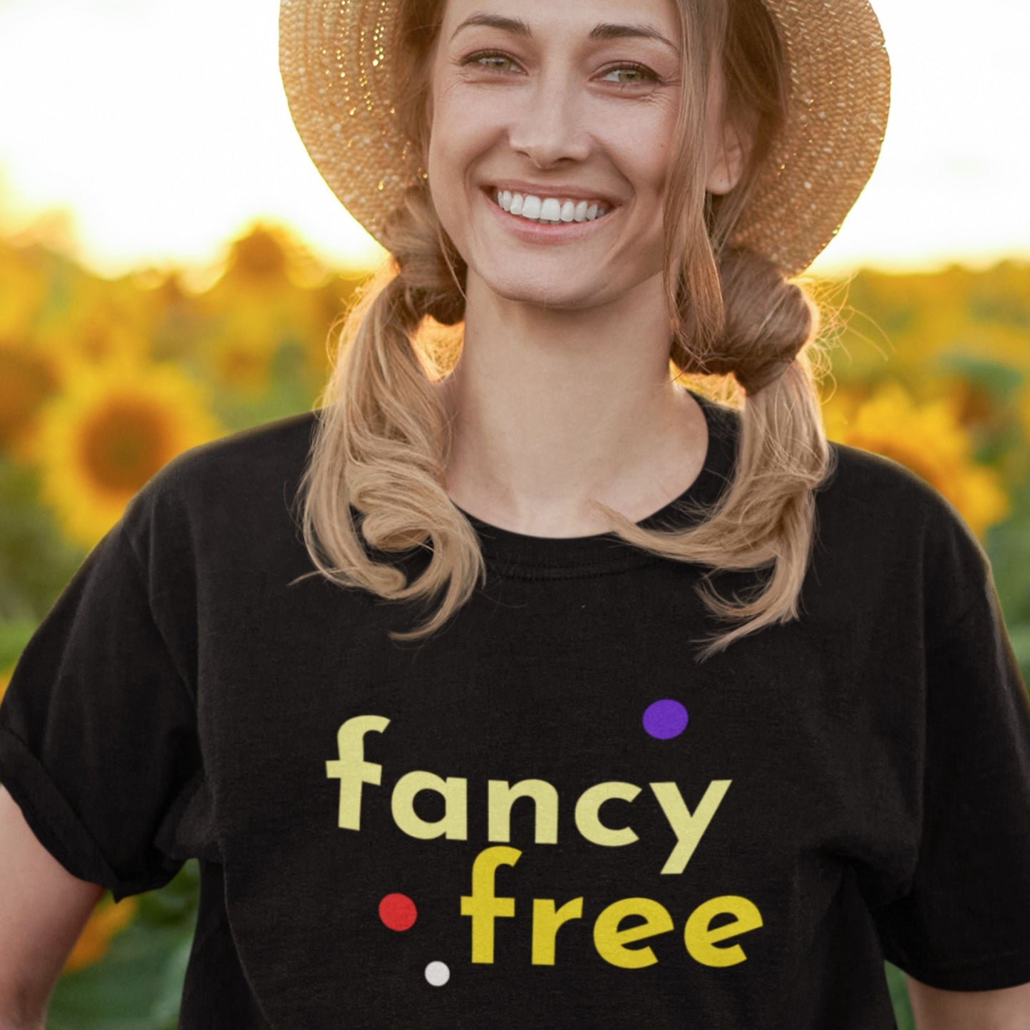 Woman wearing a black t-shirt with 'fancy .free' text in a sunflower field.