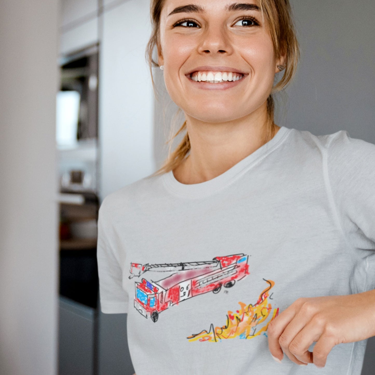 Woman wearing a grey shirt with a drawing of a fire truck and fire in a house.
