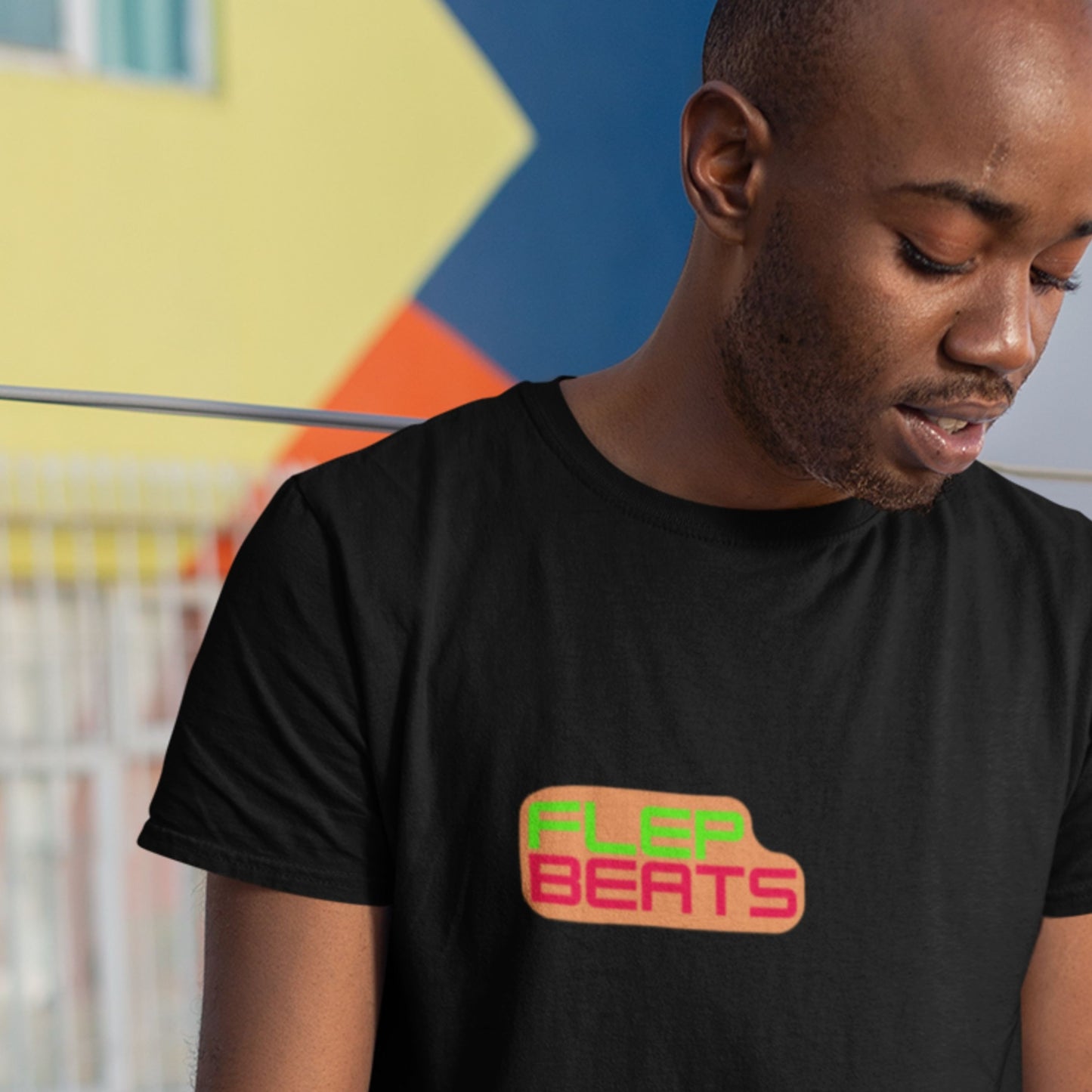 Man wearing a black t-shirt with 'FLEP BEATS' logo in front of a colorful wall.
