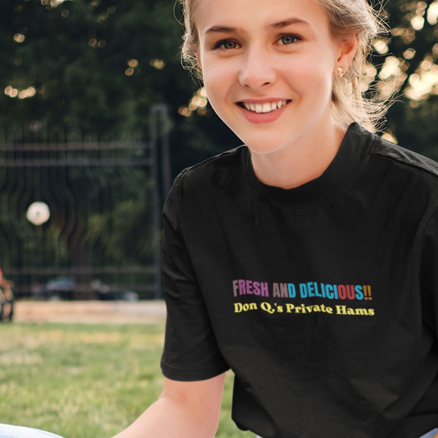Woman wearing a t-shirt with humorous colorful text in a park.