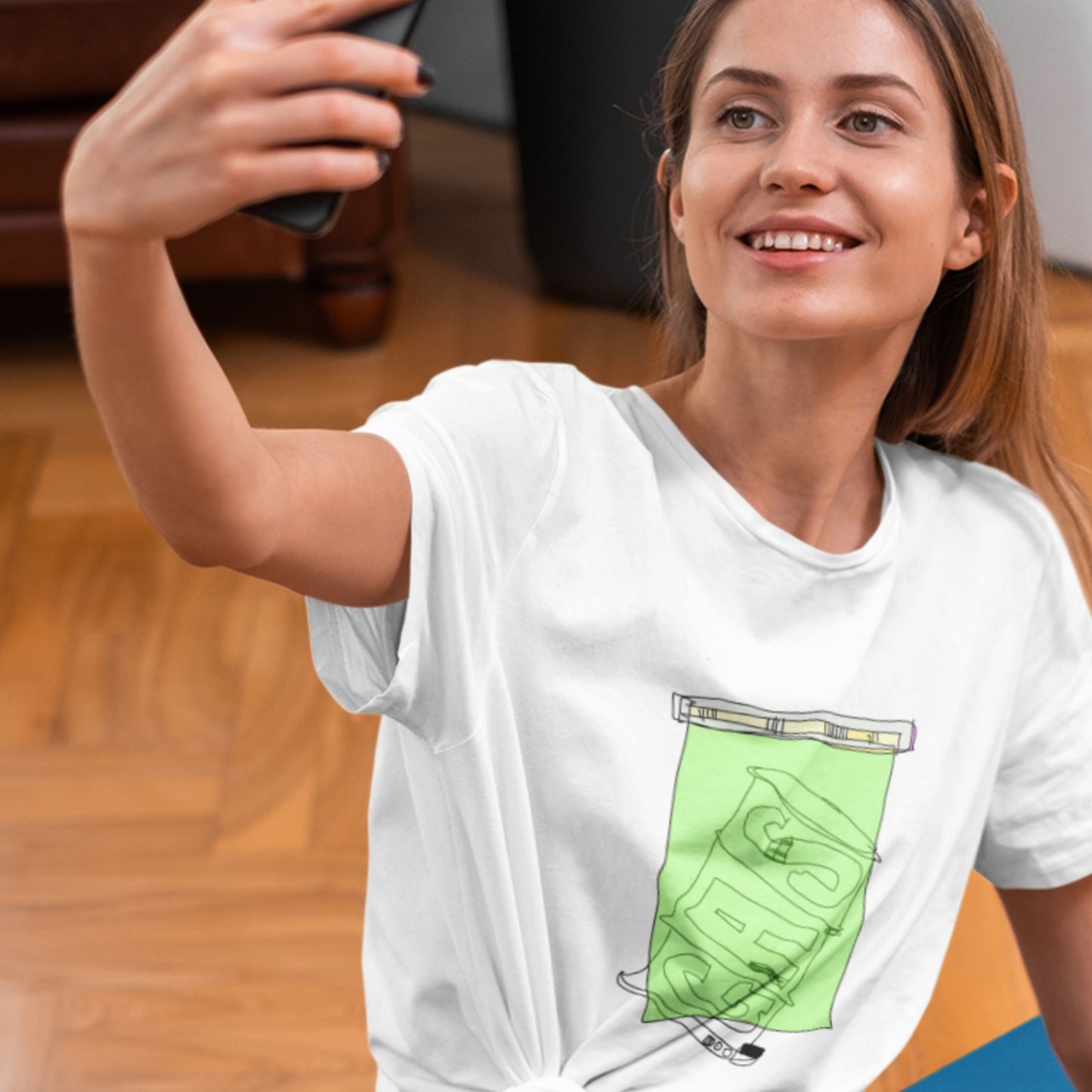 Woman taking a selfie wearing a white t-shirt with a green graphic design.