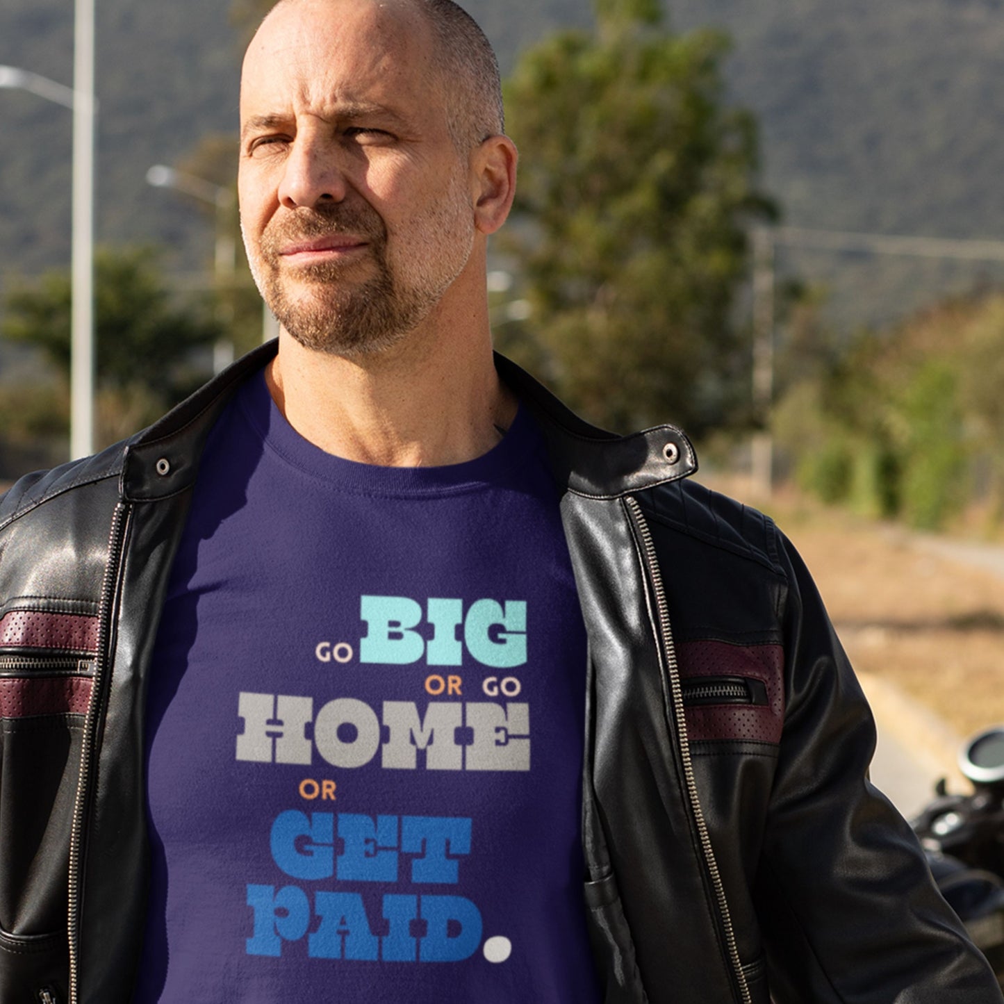 Man wearing a navy blue t-shirt with humorous colorful text on the side of a road.