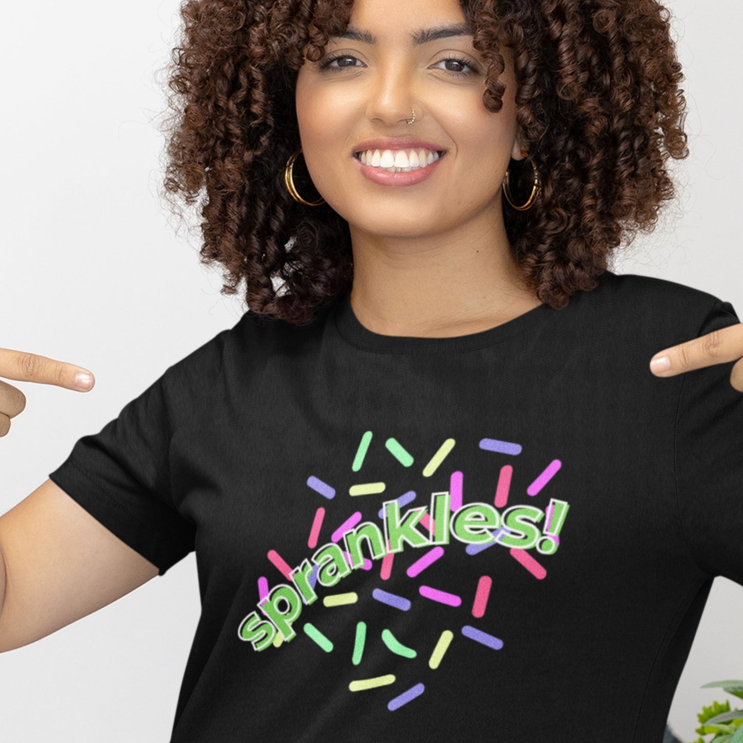 Woman wearing a black t-shirt with 'sprankles!' text and colorful design.