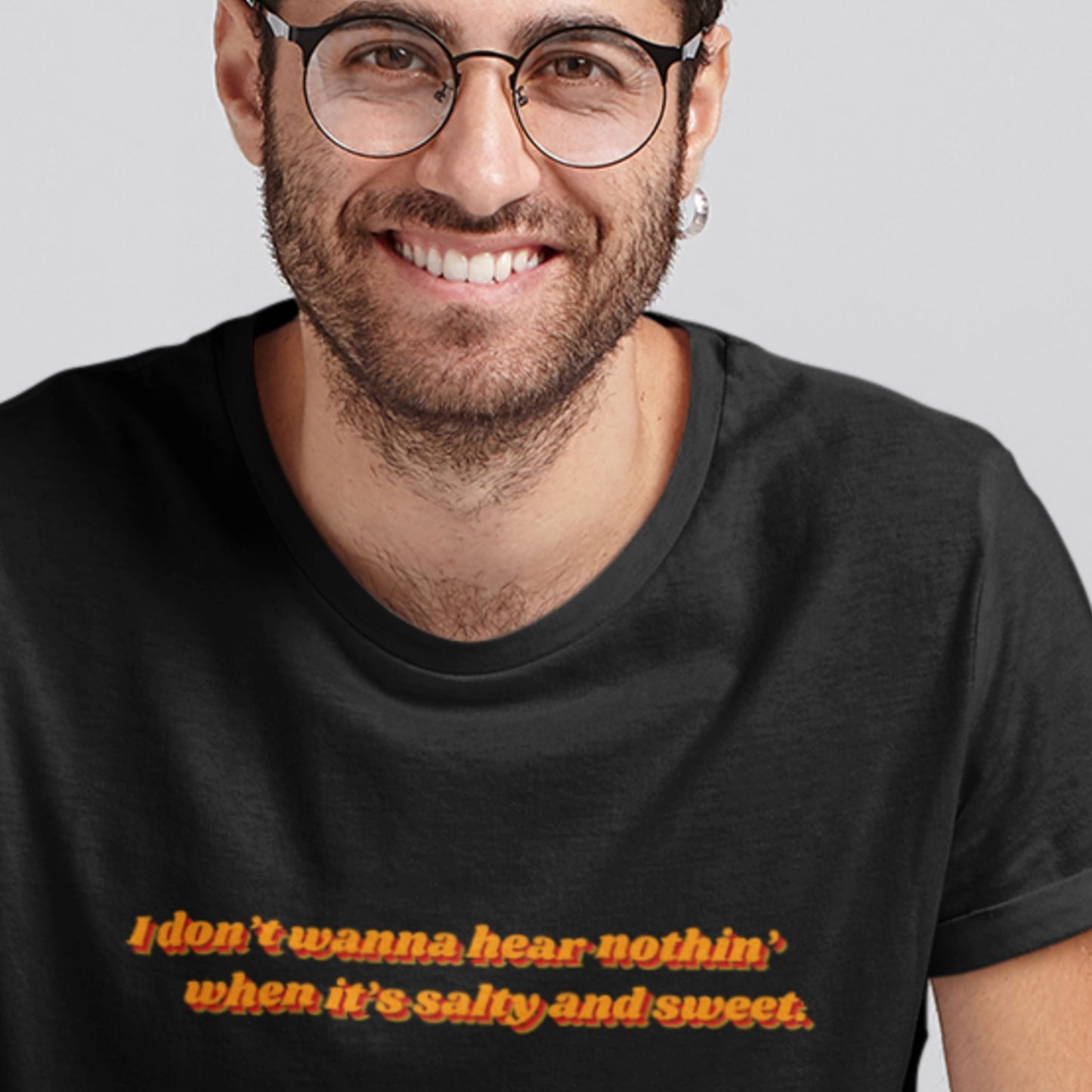 Man wearing a black t-shirt with a quote in orange text on a plain background