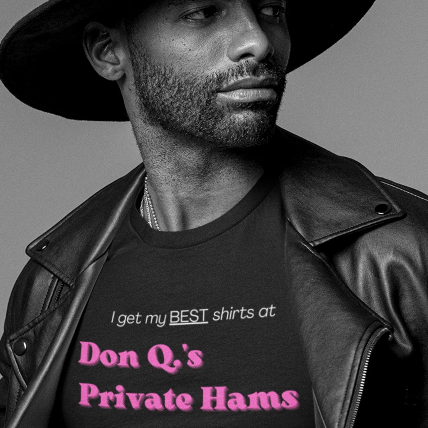 Man wearing a black leather jacket and hat, with a shirt featuring text.