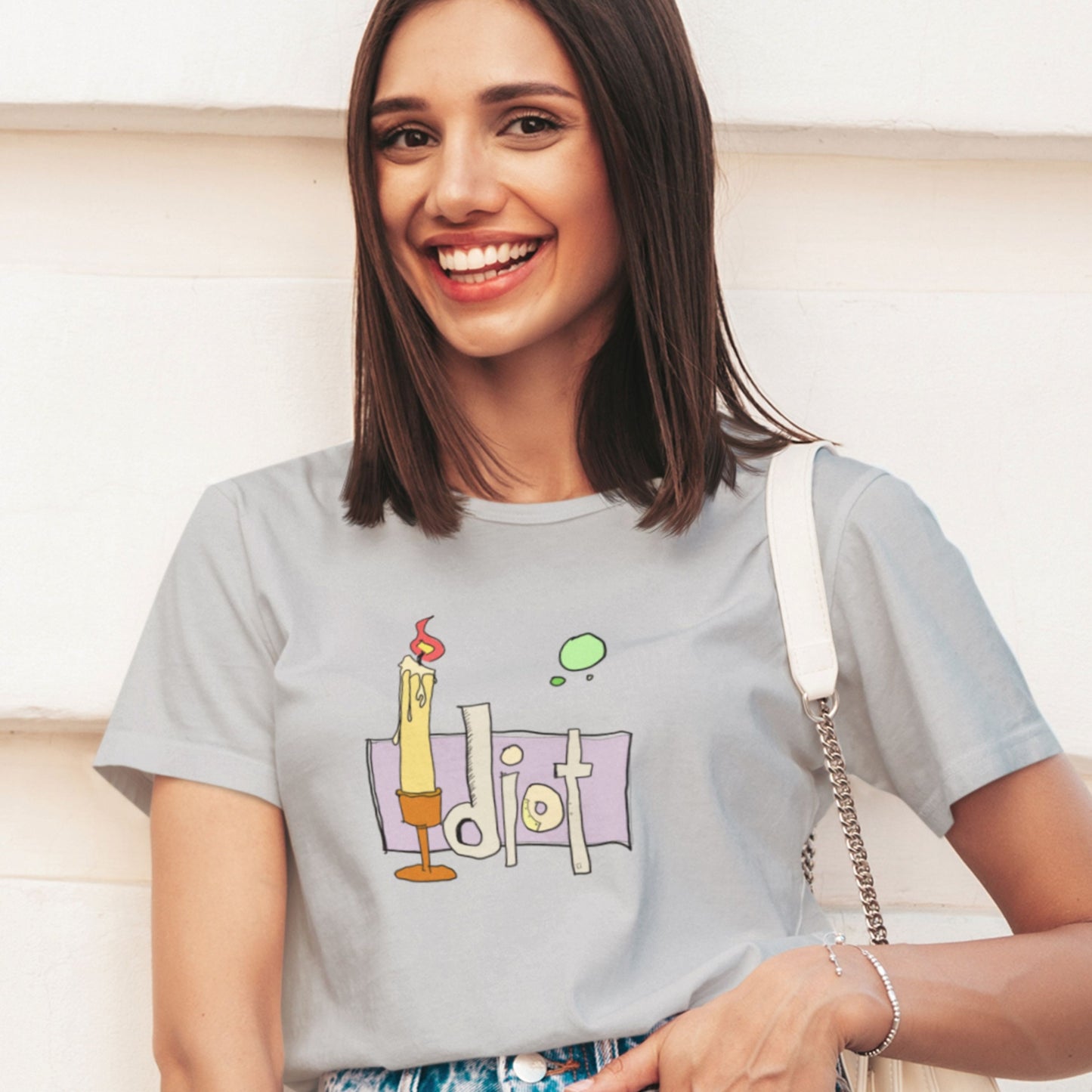 Woman wearing a light gray t-shirt with a graphic design, smiling.