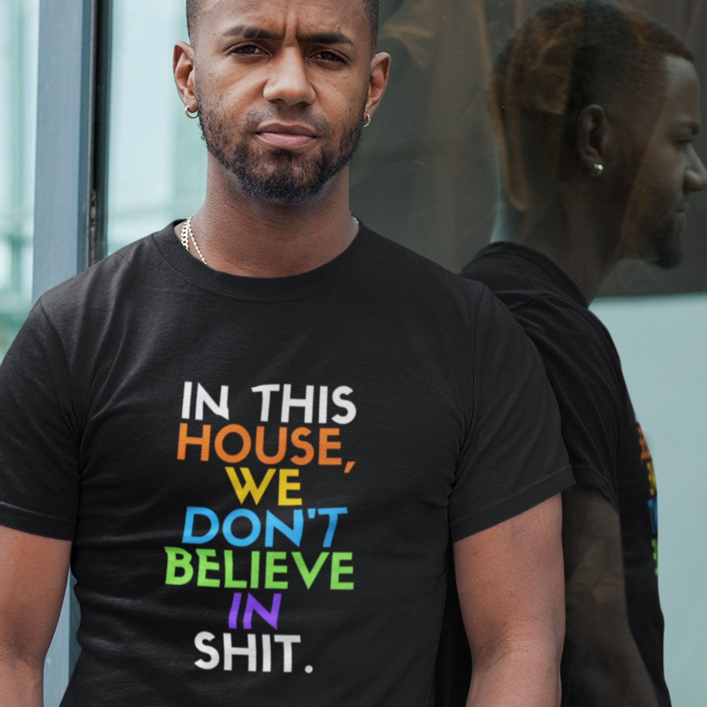 Man wearing a black t-shirt with colorful text in front of a mirror.