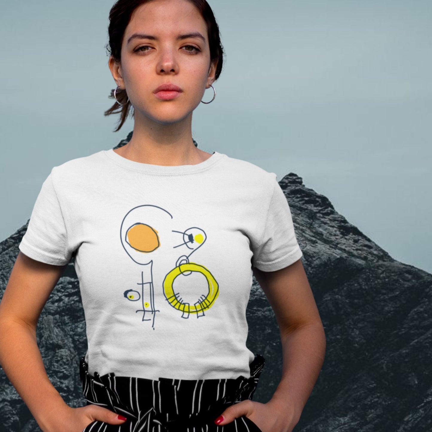 Sleepy woman wearing a white t-shirt with a colorful abstract drawing in front of a mountain.