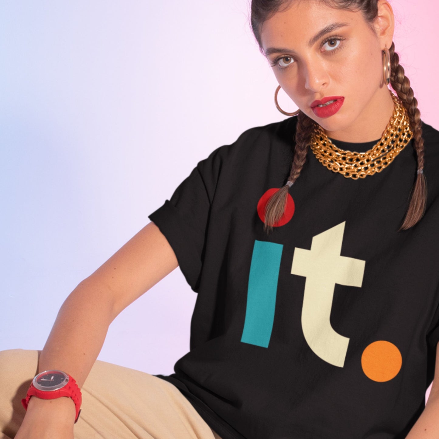 Person wearing a black t-shirt with colorful letters and a gold necklace against a light purple background.
