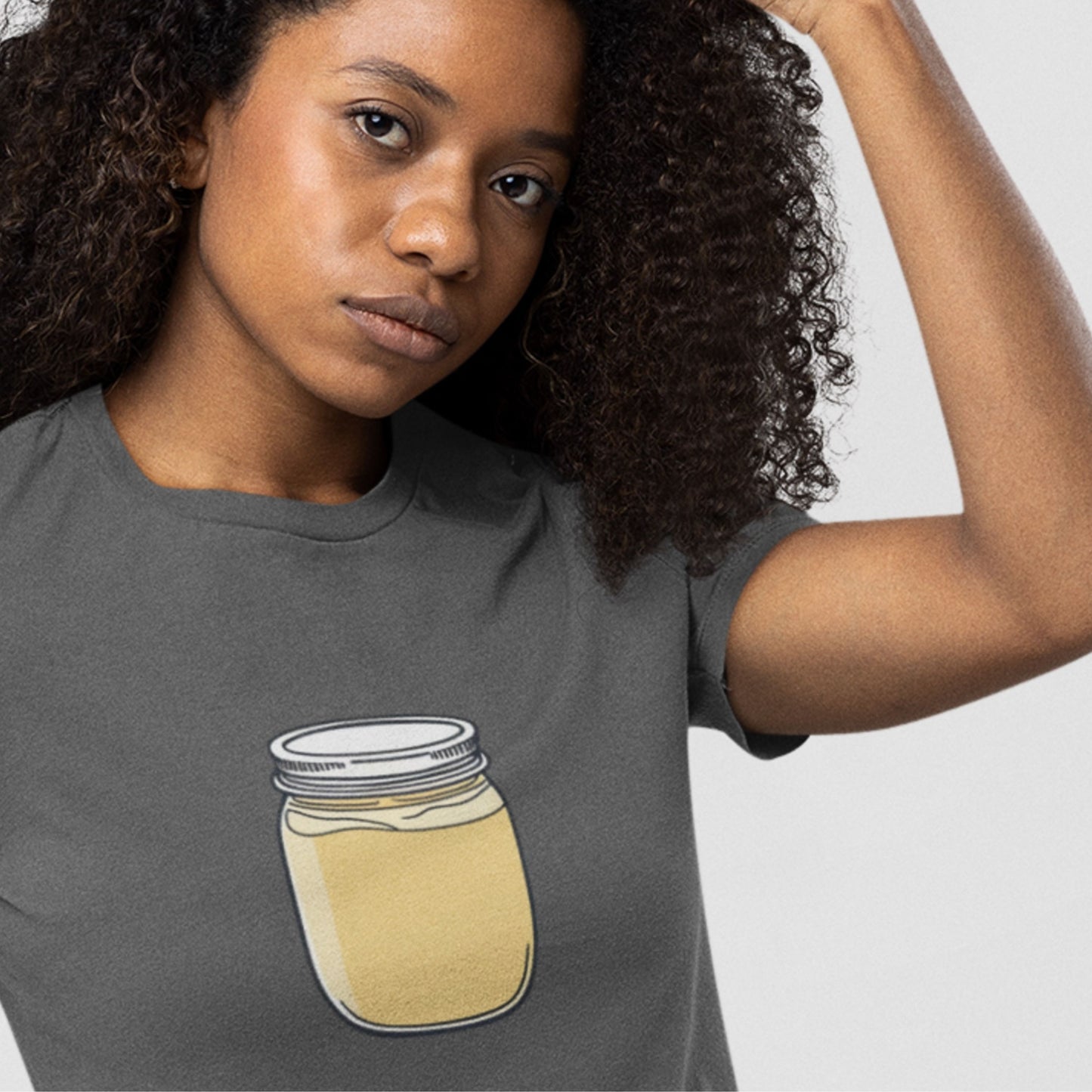 Woman wearing a grey shirt with a drawing of a jar of custard.
