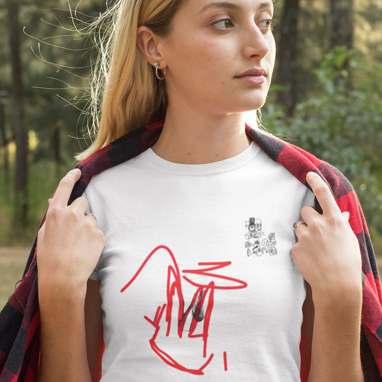 Woman wearing a white t-shirt with red and black designs outdoors.