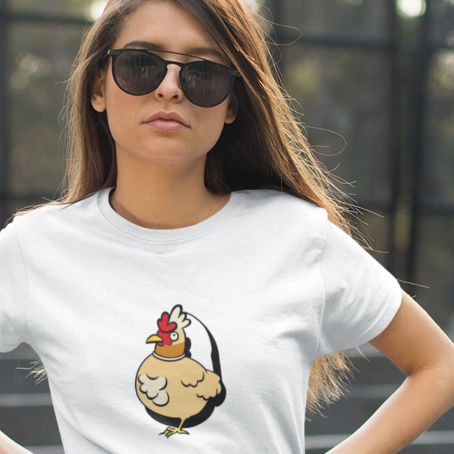 Woman wearing a white t-shirt with a cartoon chicken design outside.