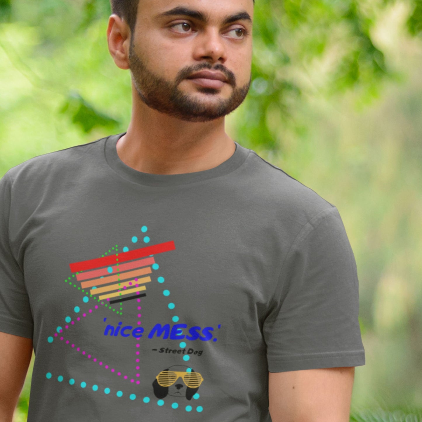 Man wearing a dark gray t-shirt with colorful design and text outdoors.