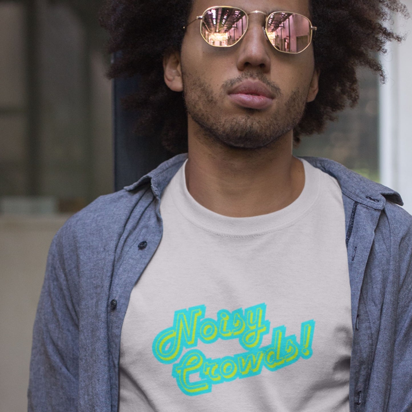 Man wearing sunglasses and a shirt with 'Noisy Crowds' text.