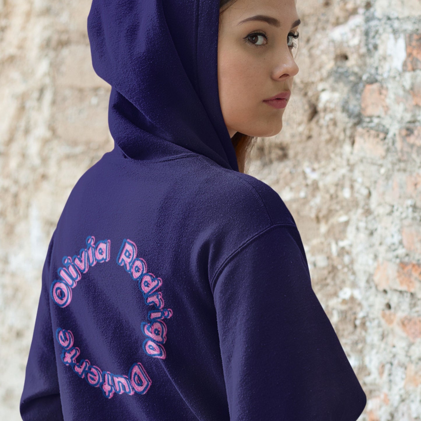 Person wearing a navy hoodie with 'Olivia Rodrigo Duterte' text on the back, standing against a textured wall.