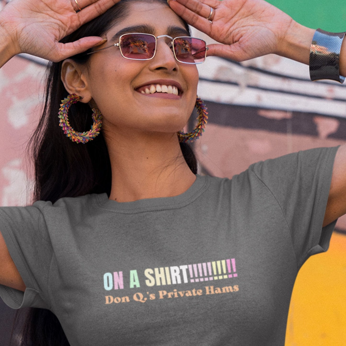 Happy woman wearing grey a t-shirt with humorous colorful text on a colorful background.