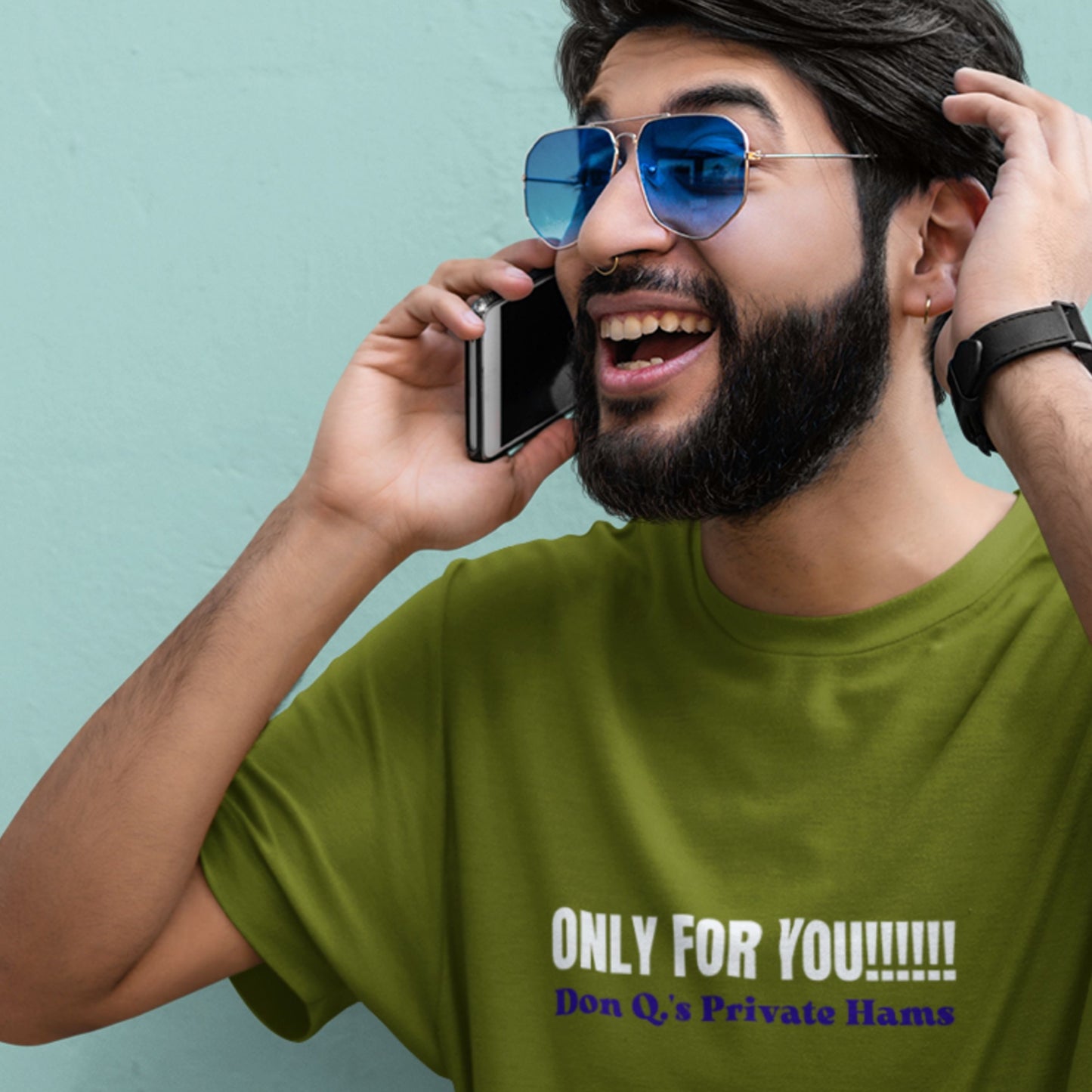 Man on phone wearing a green t-shirt with nonsensical text on a blue background.
