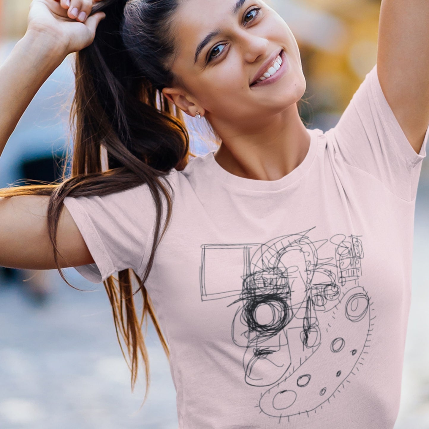 Woman wearing a pink t-shirt with a graphic design, standing outdoors.