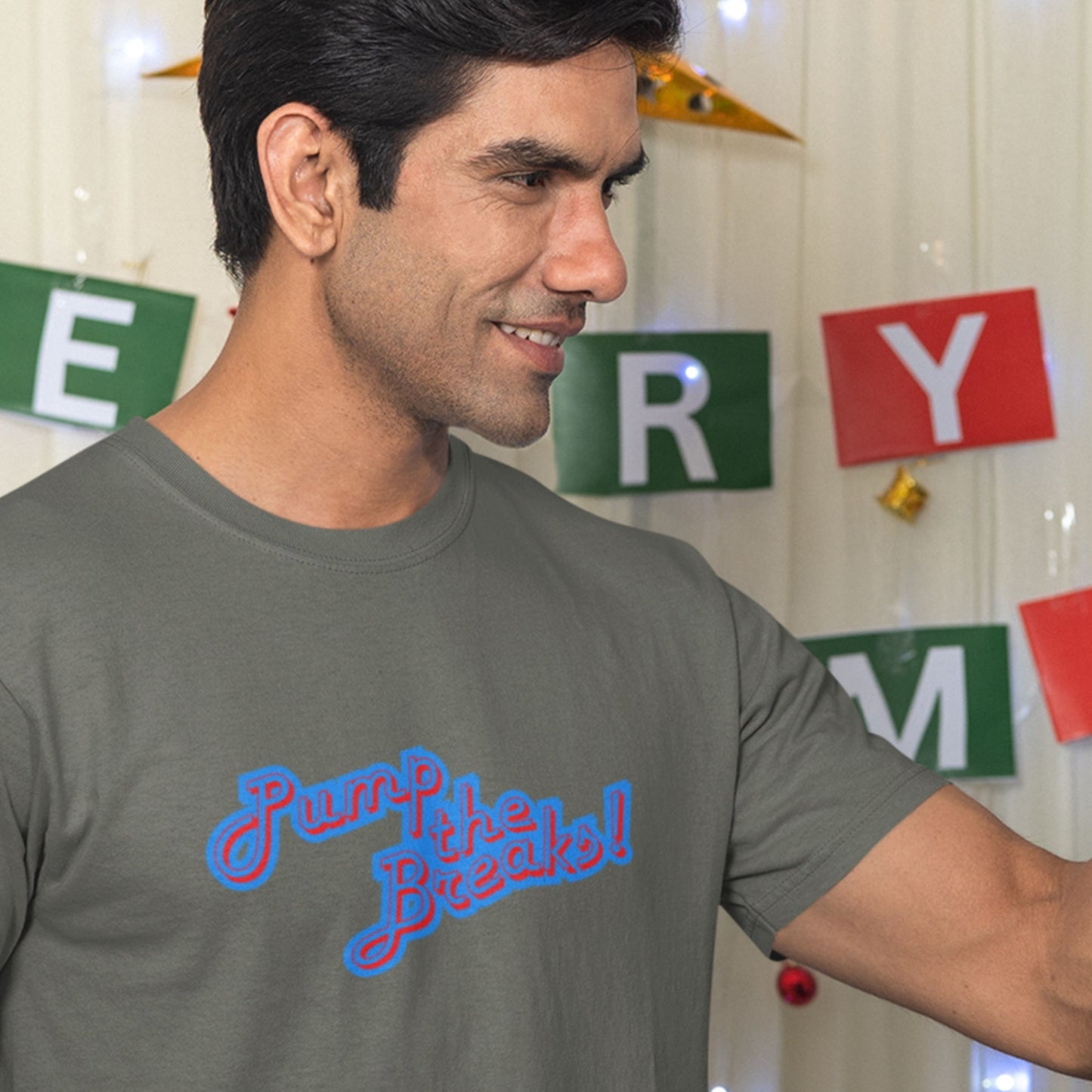 Man wearing an army green t-shirt with humorous colorful text in a room.