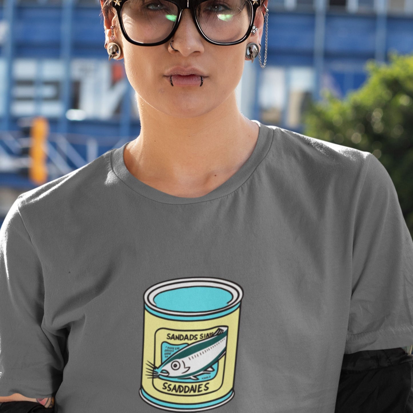 Person wearing a grey shirt with a can of fish design outside.