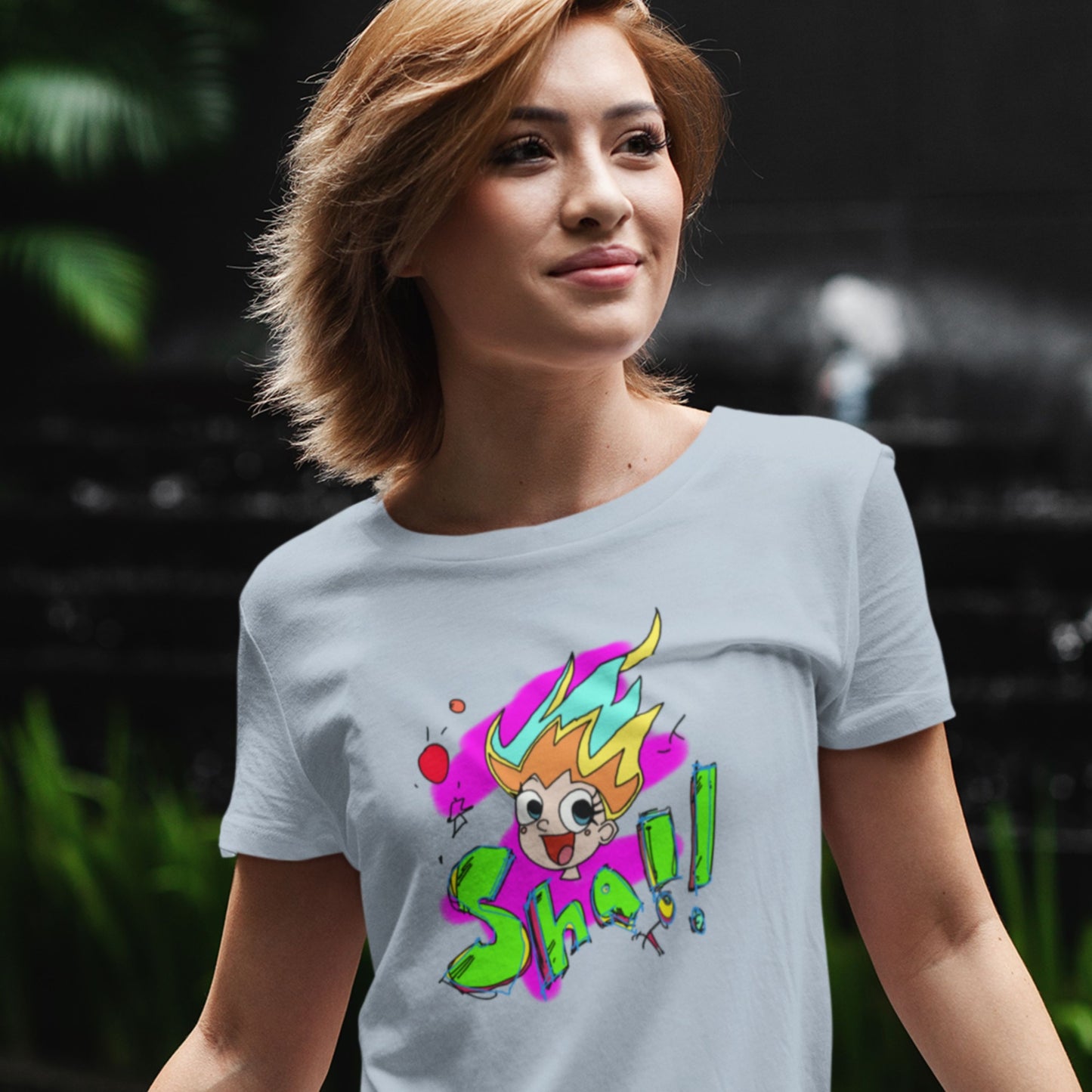 Woman wearing a gray t-shirt with colorful graphic design outdoors.