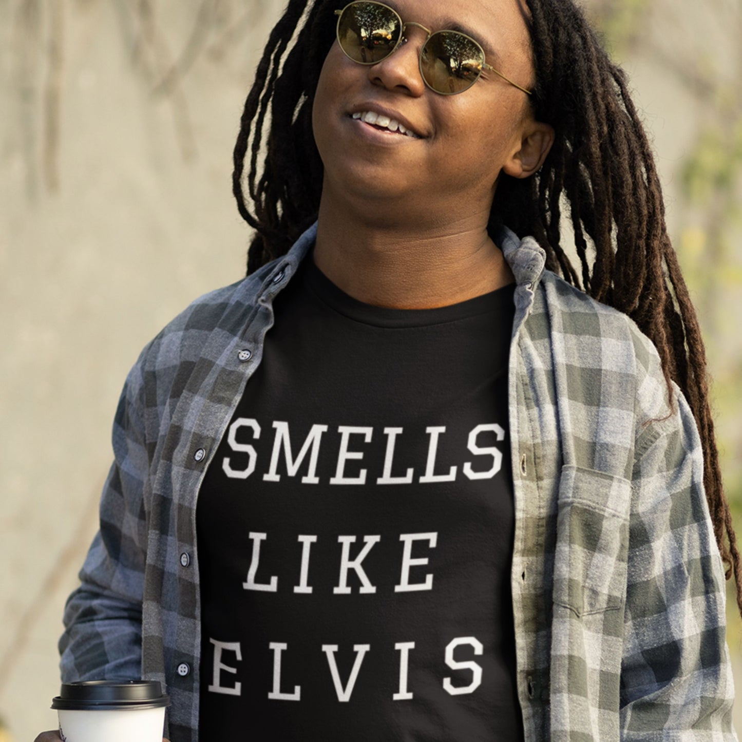 Man wearing a black t-shirt with 'smells like Elvis' text outside.
