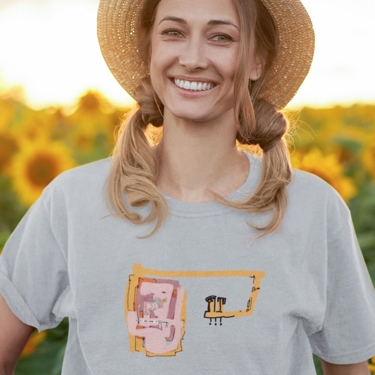 Woman in a field wearing a light blue t-shirt with a colorful abstract drawing.
