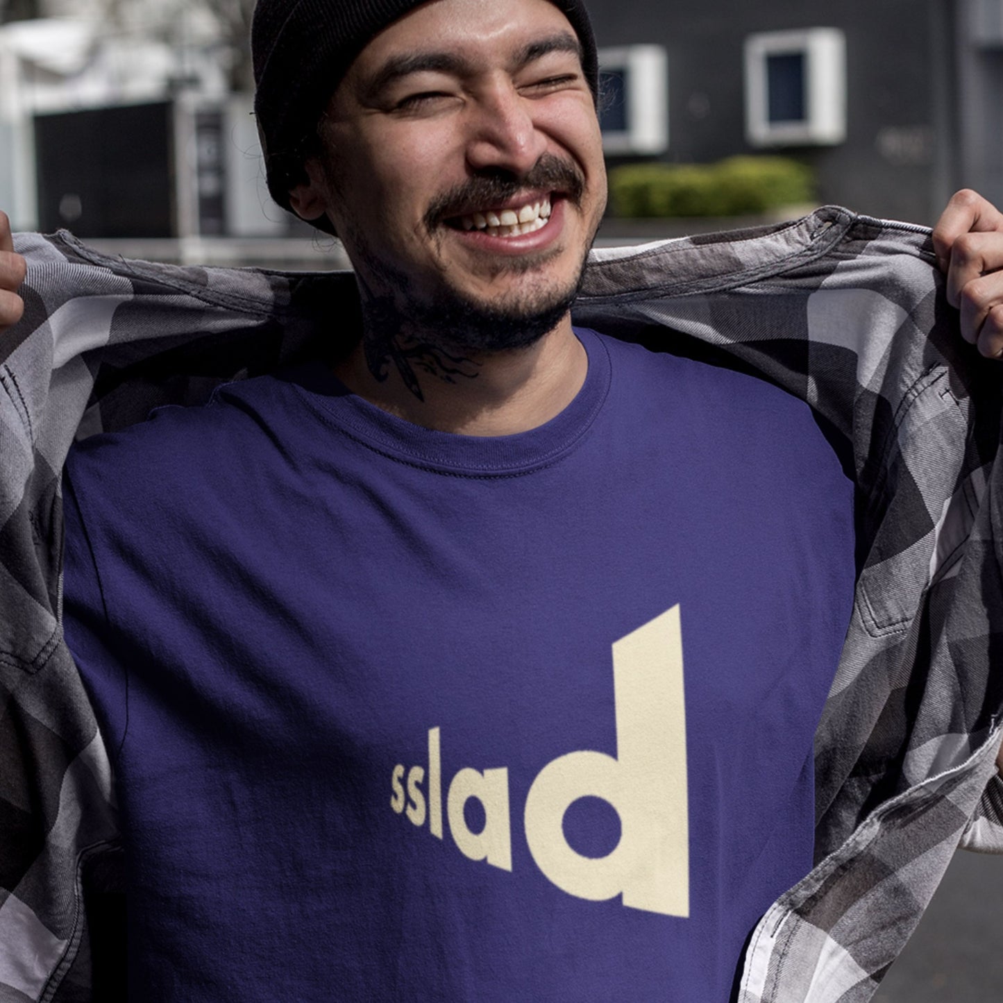 Happy man wearing a navy blue t-shirt with humorous text outside.