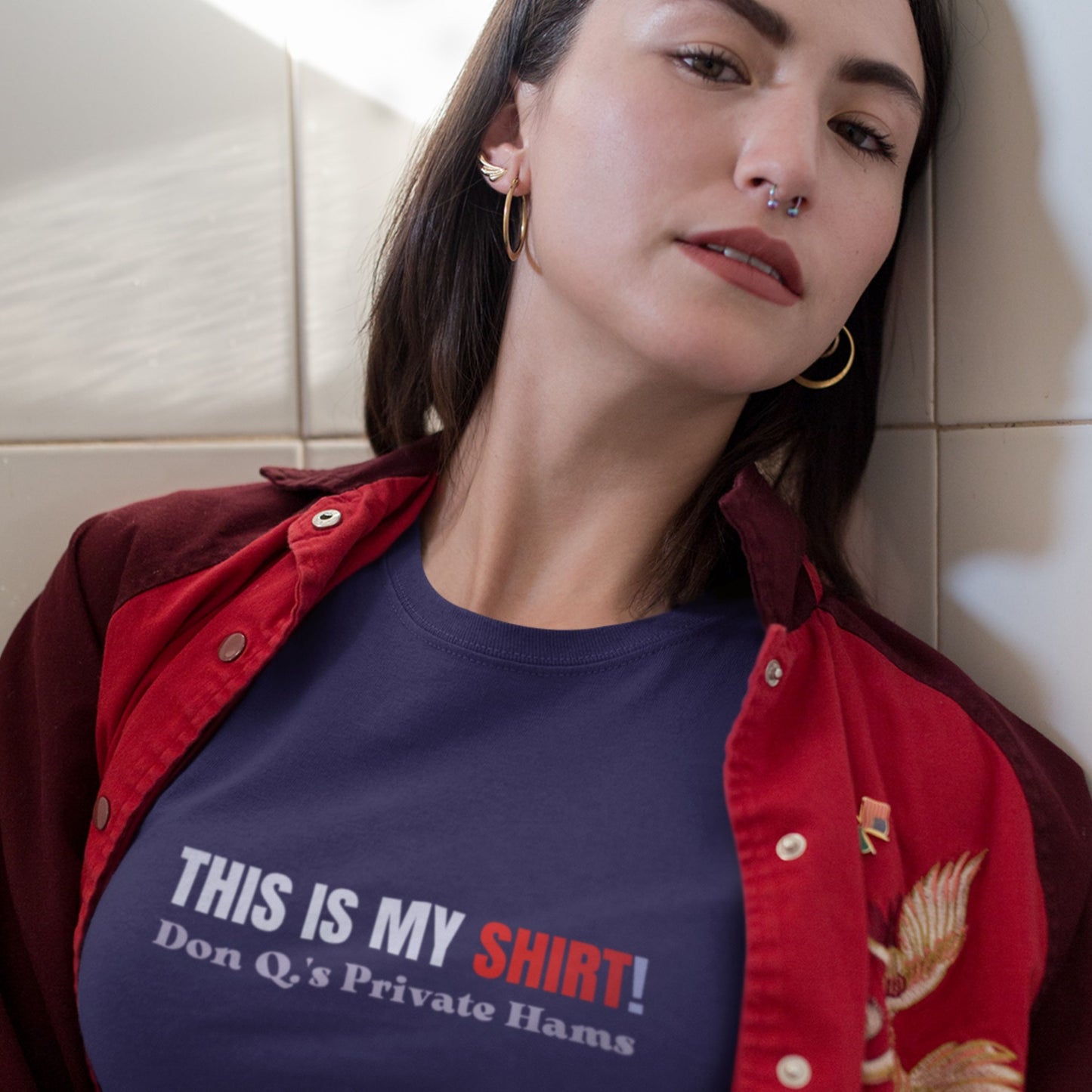 Woman wearing a navy blue t-shirt with multicolored 'THIS IS MY SHIRT!' text in a bathroom.