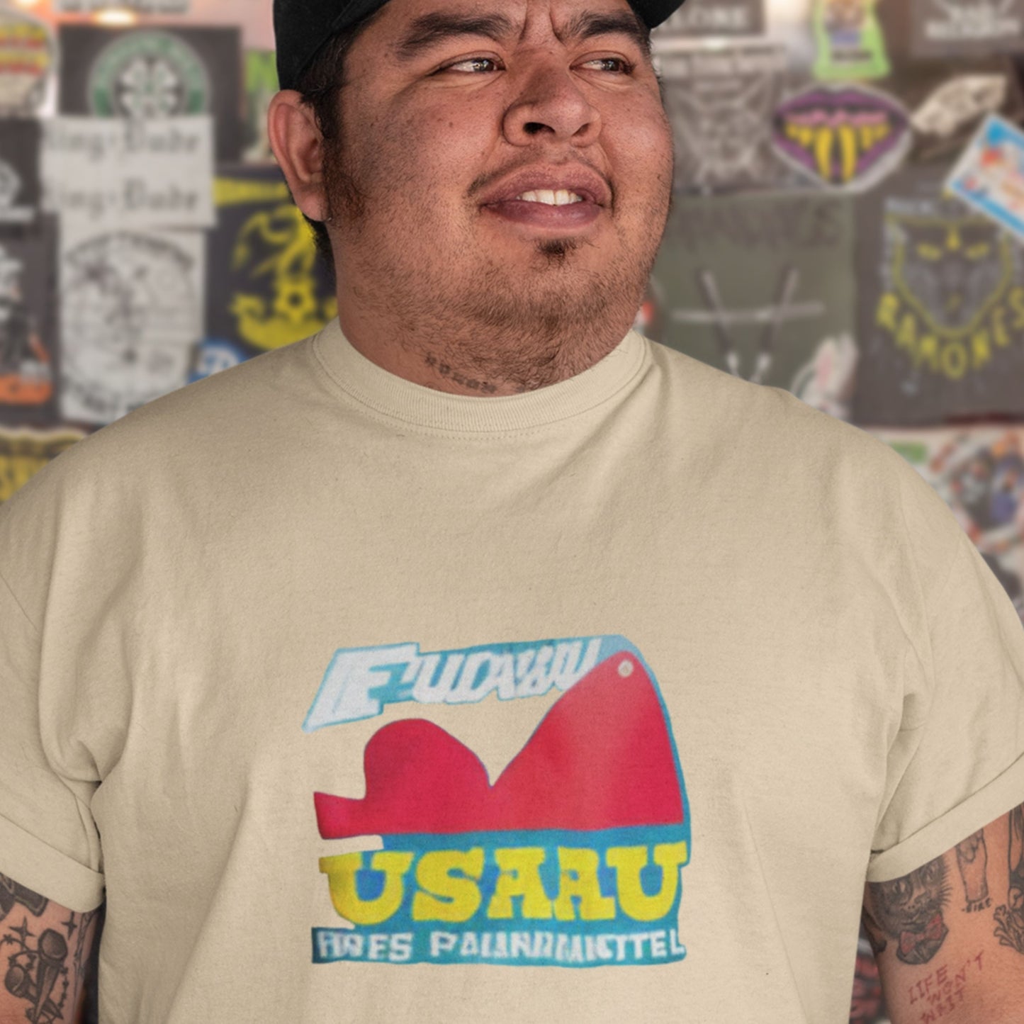 Man wearing a beige t-shirt with a fun, colorful abstract cartoon illustration in a bar.