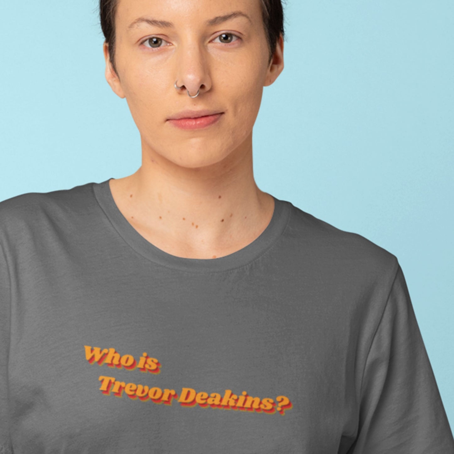 Person wearing a gray t-shirt with 'Who is Trevor Deakins?' text on a light blue background